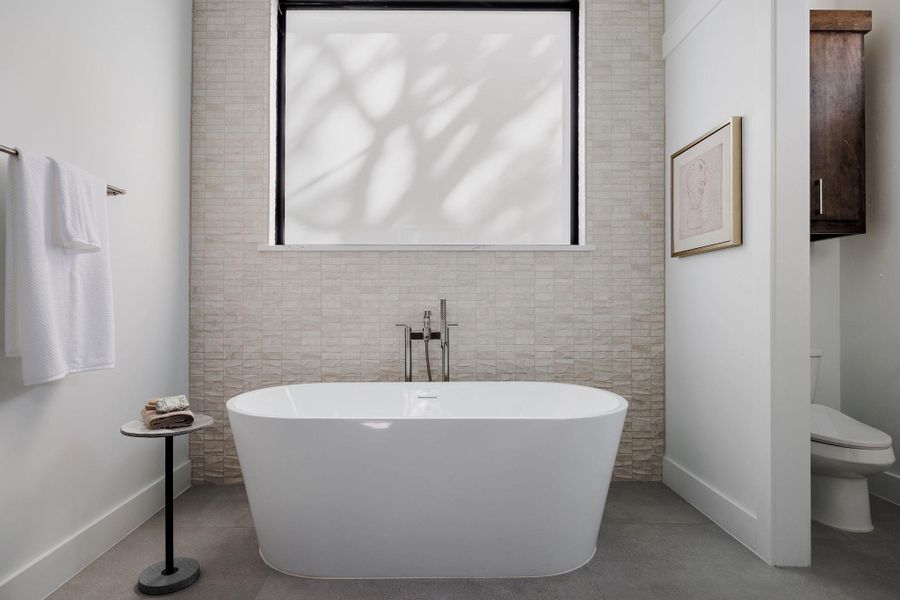 An oversized soaking tub is positioned beneath soft natural light, creating a spa-inspired focal point. An oversized soaking tub is positioned beneath soft natural light, creating a spa-inspired focal point.