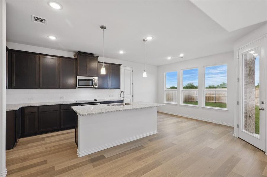 Kitchen with stainless steel microwave, a sink, backsplash, light wood finished floors, and recessed lighting Kitchen with stainless steel microwave, a sink, backsplash, light wood finished floors, and recessed lighting