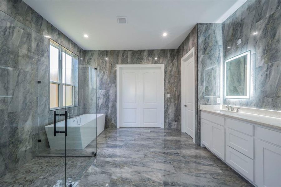 Full bathroom featuring tile walls, a freestanding tub, dark marble finish floors, vanity, and recessed lighting Full bathroom featuring tile walls, a freestanding tub, dark marble finish floors, vanity, and recessed lighting