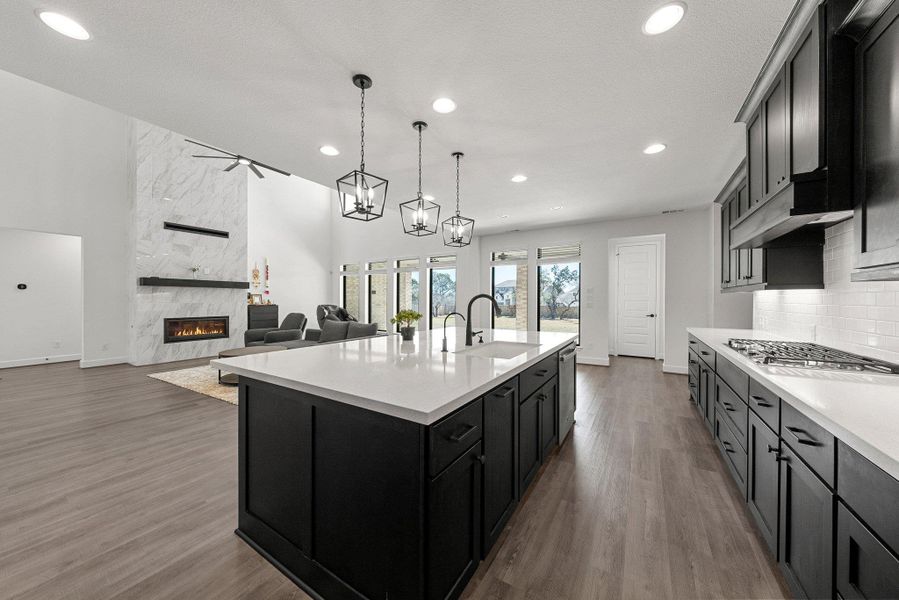 Kitchen featuring a fireplace, stainless steel appliances, light countertops, decorative backsplash, and a sink