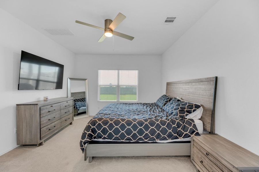 Bedroom with visible vents, light colored carpet, and ceiling fan
