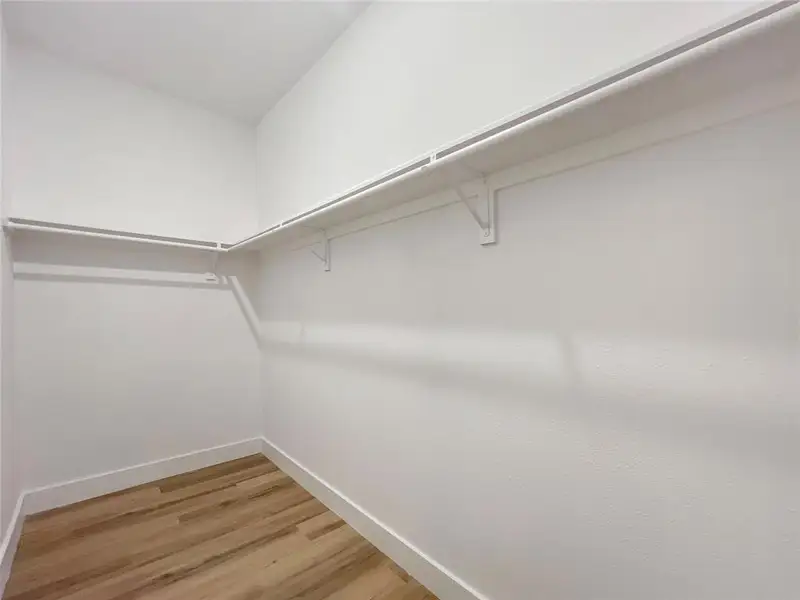 Spacious closet with light wood-type flooring Spacious closet with light wood-type flooring