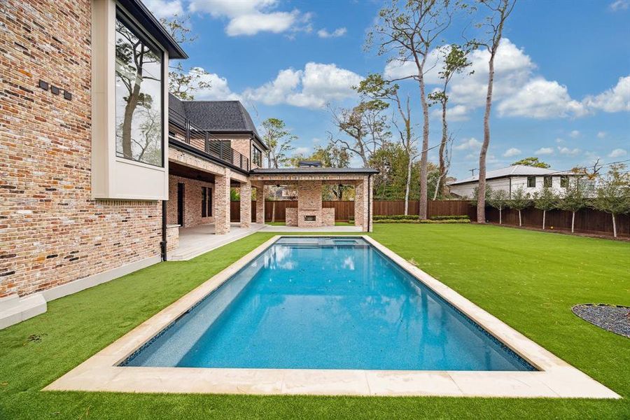 A stunning backyard retreat featuring a perfectly symmetrical pool with crisp, straight lines that seamlessly complement the back patio. Also to the side of the pool is a private outdoor pool bath with a full shower.