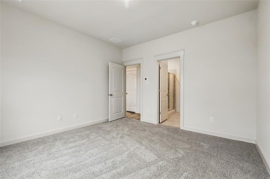 Unfurnished bedroom with light carpet and ensuite bathroom