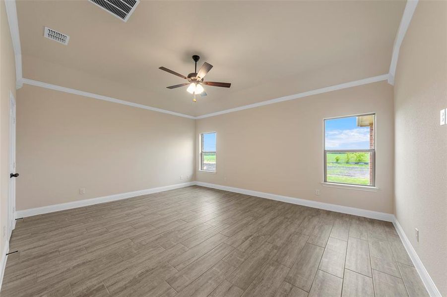 Empty room featuring ornamental molding, a ceiling fan, wood finished floors, and baseboards