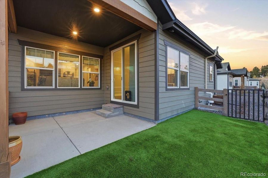 The back yard has a fenced area and artificial turf.