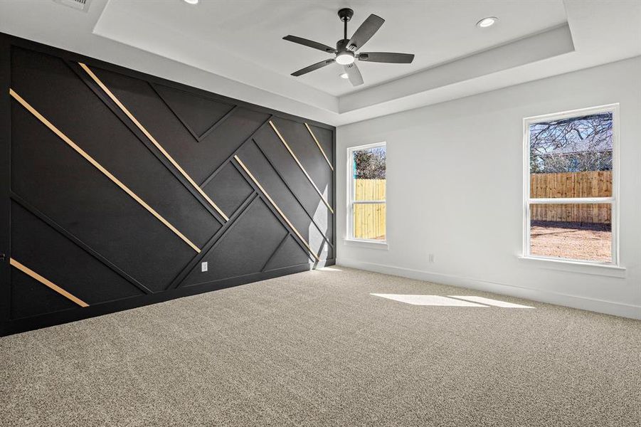 Empty room featuring carpet floors, recessed lighting, a raised ceiling, ceiling fan, and baseboards