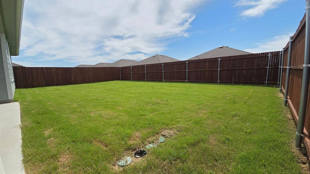 Expansive backyard featuring a lush lawn, privacy fencing, and a concrete patio Expansive backyard featuring a lush lawn, privacy fencing, and a concrete patio