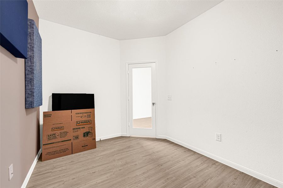 Versatile open space with warm wood-look flooring and clean neutral walls.