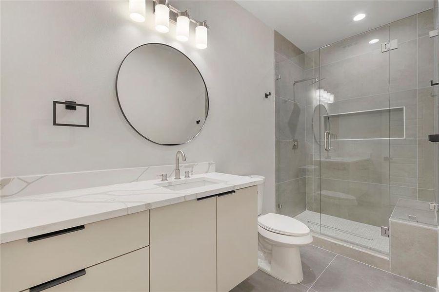 Bathroom with tile patterned floors, a shower with door, toilet, and vanity