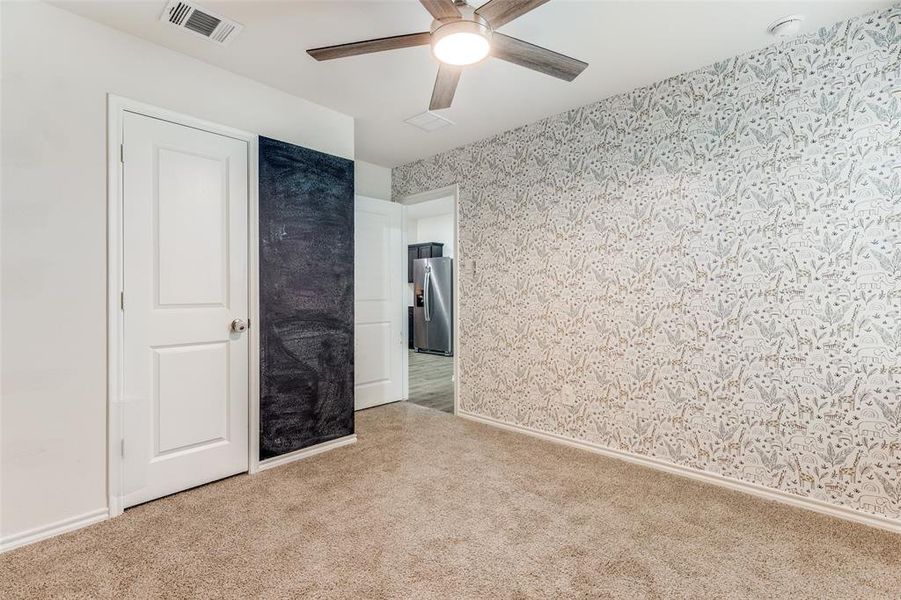 Room featuring patterned wallpaper, neutral carpet, and a ceiling fan with integrated lighting Room featuring patterned wallpaper, neutral carpet, and a ceiling fan with integrated lighting