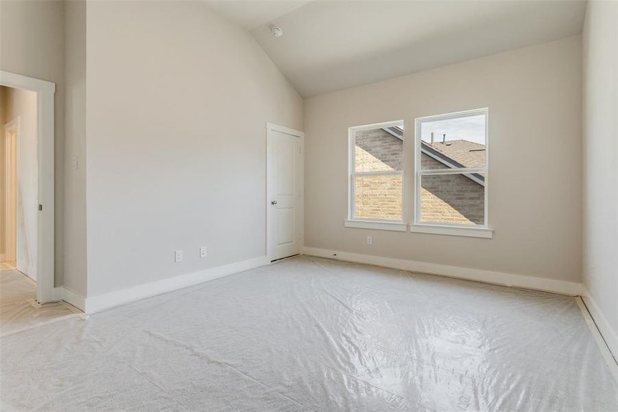 Empty room with light carpet and lofted ceiling