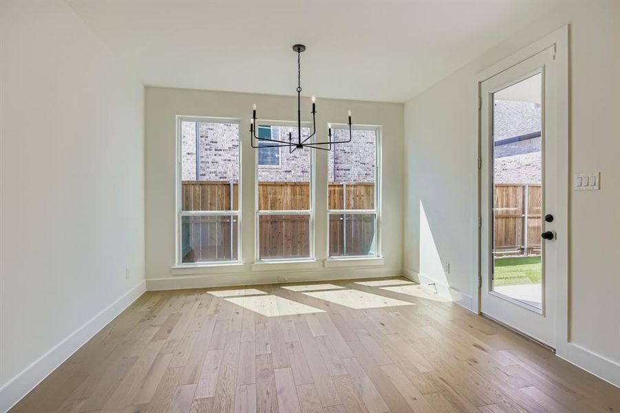 Unfurnished dining area with a chandelier and light wood-type flooring