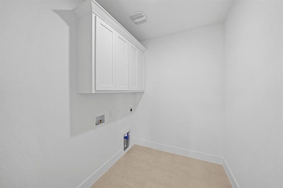 Washroom featuring hookup for an electric dryer, cabinet space, light tile patterned floors, and hookup for a washing machine Washroom featuring hookup for an electric dryer, cabinet space, light tile patterned floors, and hookup for a washing machine