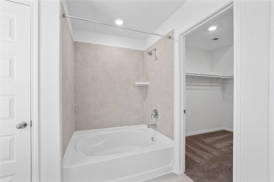 Primary bathroom tub/shower combination with tile surround and the large walk-in closet. Primary bathroom tub/shower combination with tile surround and the large walk-in closet.