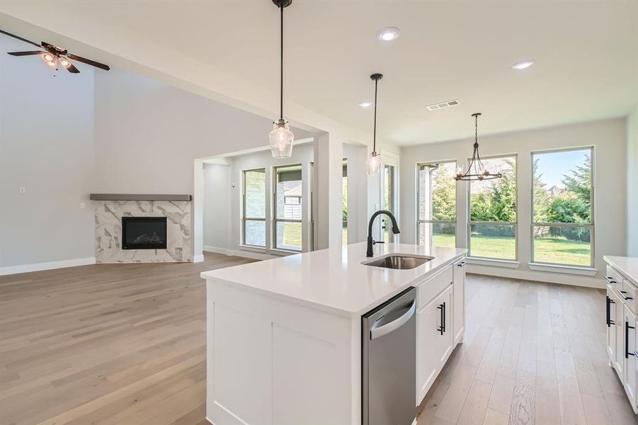 Kitchen with pendant lighting, stainless steel dishwasher, sink, and an island with sink