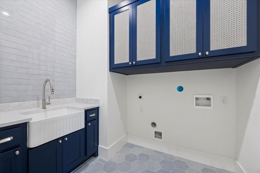 Stylish second-floor laundry room featuring hexagon tile flooring, a quartz countertop, farmhouse-style porcelain basin sink, and ample storage—designed to make laundry day more enjoyable.