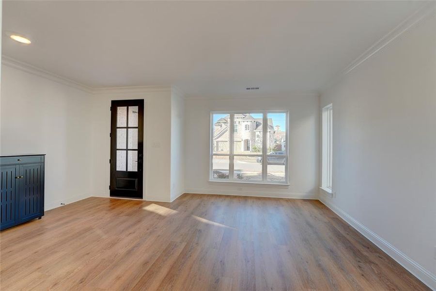 Foyer entrance with ornamental molding, vinyl flooring, visible vents, and baseboards