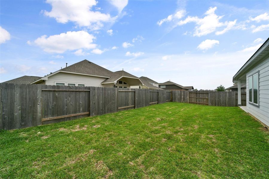 Spacious, well-maintained backyard featuring a lush lawn and a wooden privacy fence, perfect for outdoor activities and gatherings.