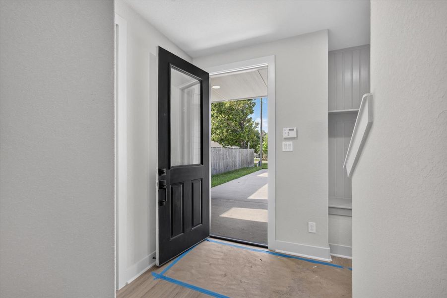 This entryway features a modern design with a large windowed door, stylish dark walls, and wood flooring. There is a cozy nook with seating and shelving, plus a small window for natural light. A staircase leads upward, adding to the home's welcoming ambiance. This entryway features a modern design with a large windowed door, stylish dark walls, and wood flooring. There is a cozy nook with seating and shelving, plus a small window for natural light. A staircase leads upward, adding to the home's welcoming ambiance.