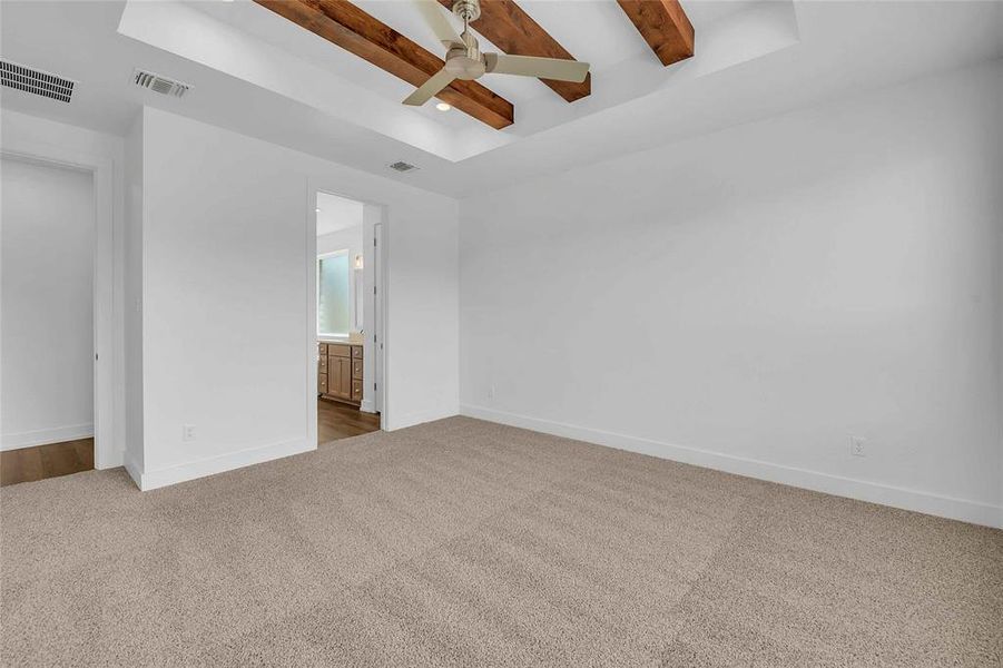 Empty room with visible vents, ceiling fan, beam ceiling, and carpet floors Empty room with visible vents, ceiling fan, beam ceiling, and carpet floors