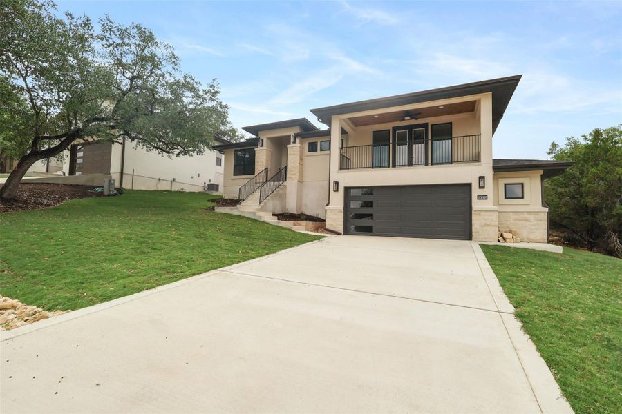 View of front of property featuring stone siding, a garage, stucco siding, and a balcony View of front of property featuring stone siding, a garage, stucco siding, and a balcony