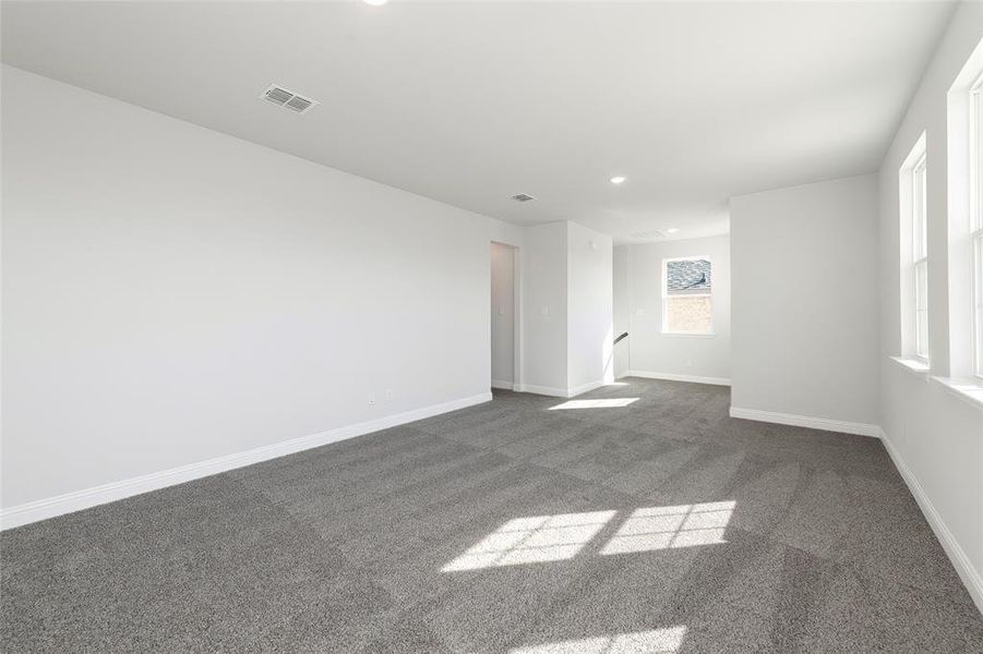 Empty room with dark colored carpet, recessed lighting, and baseboards Empty room with dark colored carpet, recessed lighting, and baseboards
