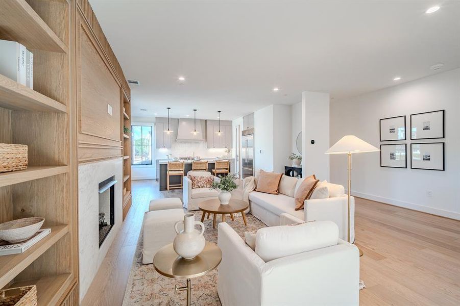 Living room with a fireplace, light wood-type flooring, and recessed lighting
