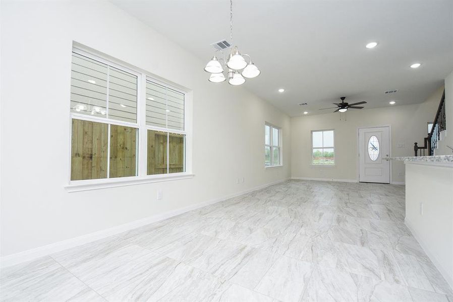 Spacious living with large windows, ceiling fans, and modern lighting fixtures in a new home.