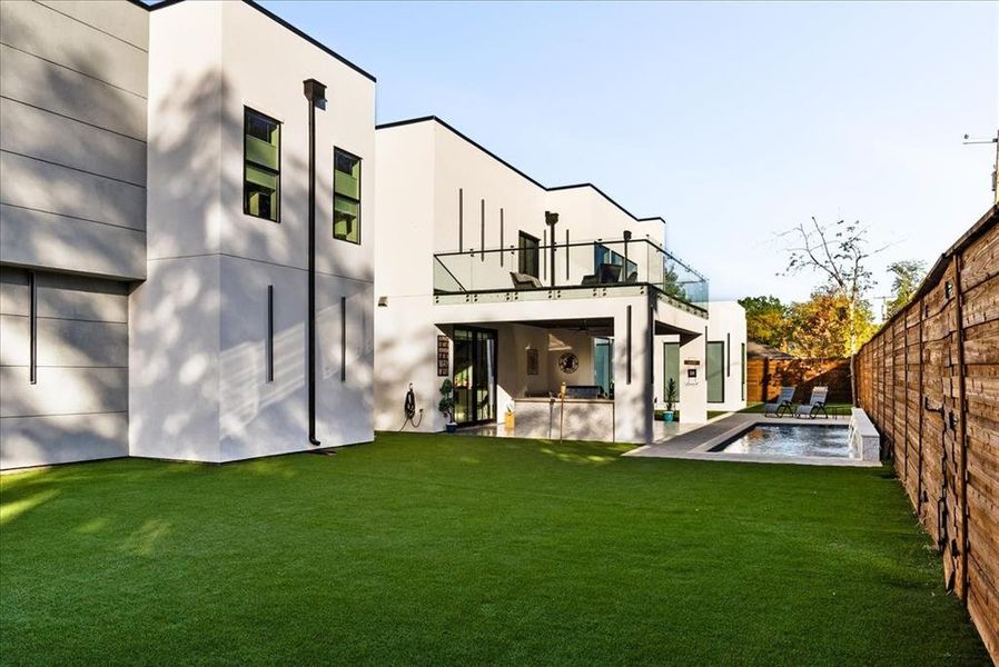 Back yard fully turfed, a fenced in pool, patio area, and view to balcony above