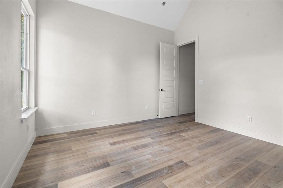 Spare room featuring light wood-type flooring and high vaulted ceiling