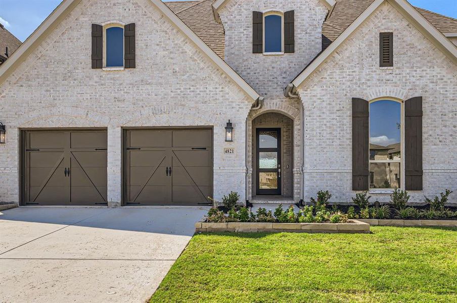 French country style house with a garage and a front lawn