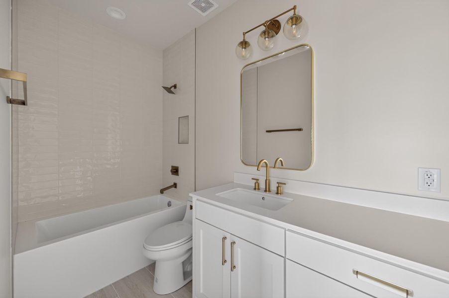 Elegant gold hardware pairs beautifully with a clean white vanity and classic tiled alcove tub.