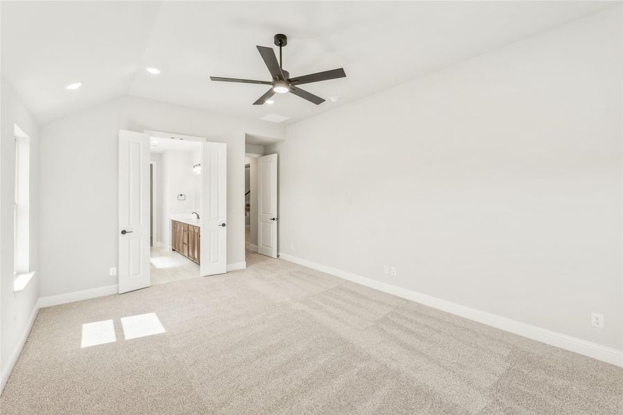 Empty bedroom with carpet, ceiling fan, and open door to ensuite bathroom Empty bedroom with carpet, ceiling fan, and open door to ensuite bathroom