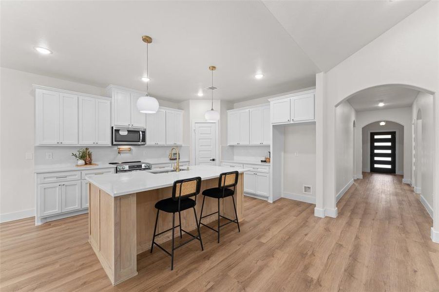 Kitchen with stainless steel appliances, a sink, arched walkways, white cabinets, and recessed lighting Kitchen with stainless steel appliances, a sink, arched walkways, white cabinets, and recessed lighting