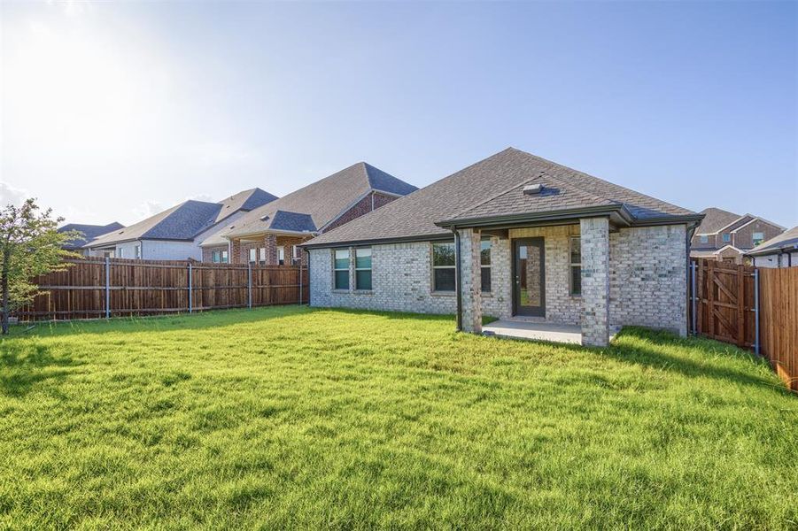Rear view of house featuring brick siding, a fenced backyard, a shingled roof, and a patio area Rear view of house featuring brick siding, a fenced backyard, a shingled roof, and a patio area