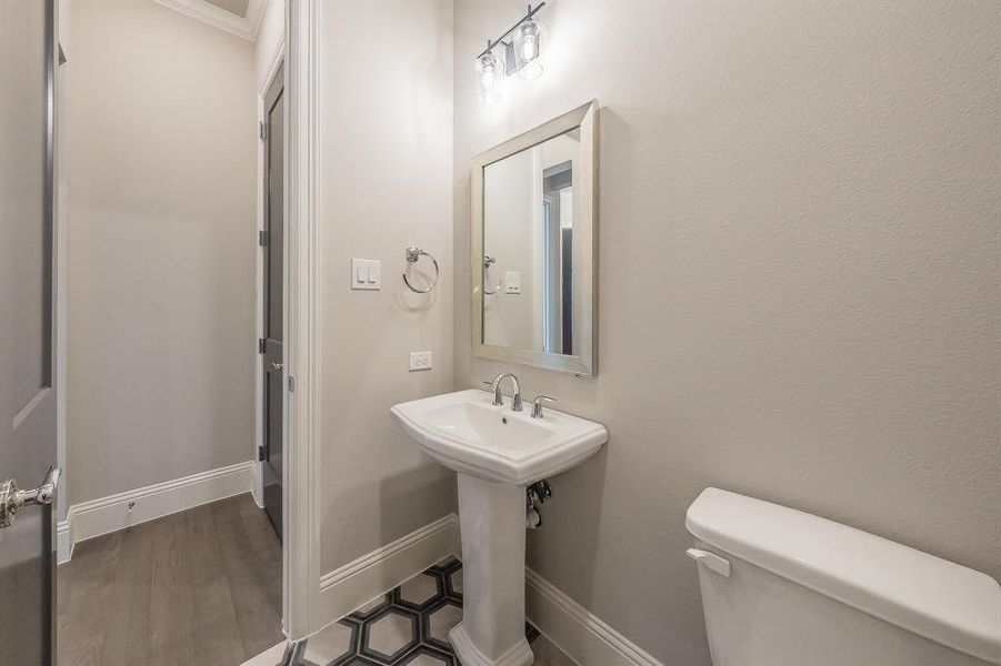 Pedestal sink with chrome fixtures and a framed vanity mirror