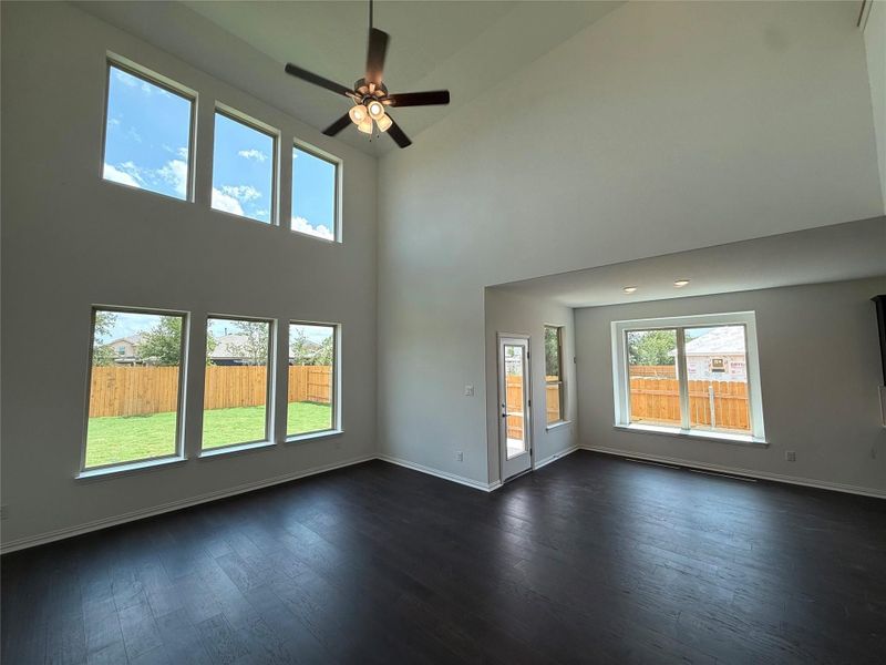 Unfurnished living room featuring high vaulted ceiling, dark wood-style flooring, and ceiling fan Unfurnished living room featuring high vaulted ceiling, dark wood-style flooring, and ceiling fan