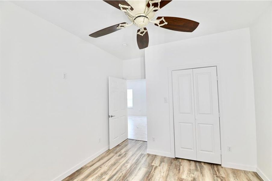 bedroom with light hardwood / wood-style flooring, ceiling fan, and a closet