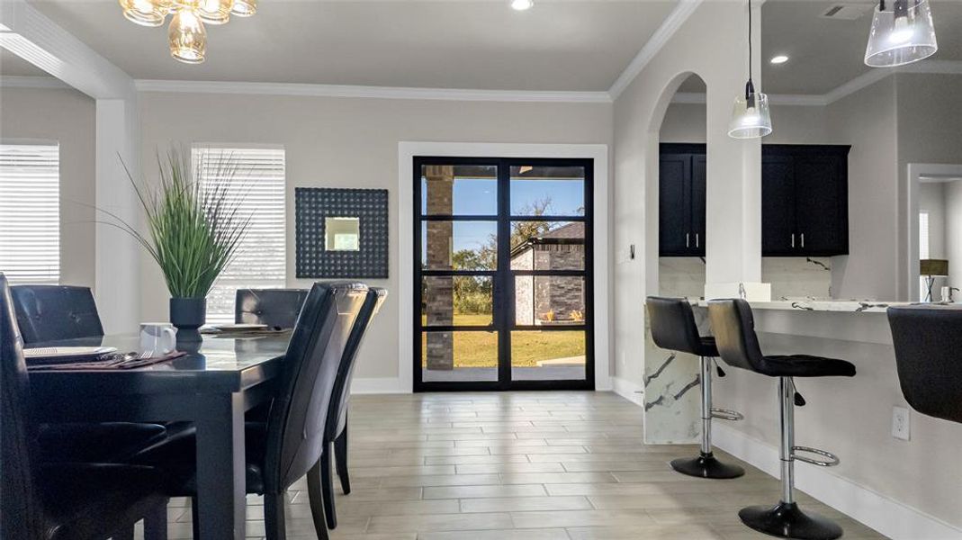 Dining area with ornamental molding and light wood-type flooring