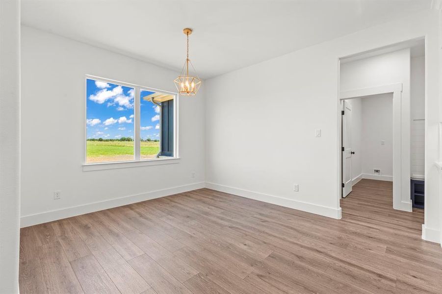 Spare room featuring a chandelier and light wood-type flooring