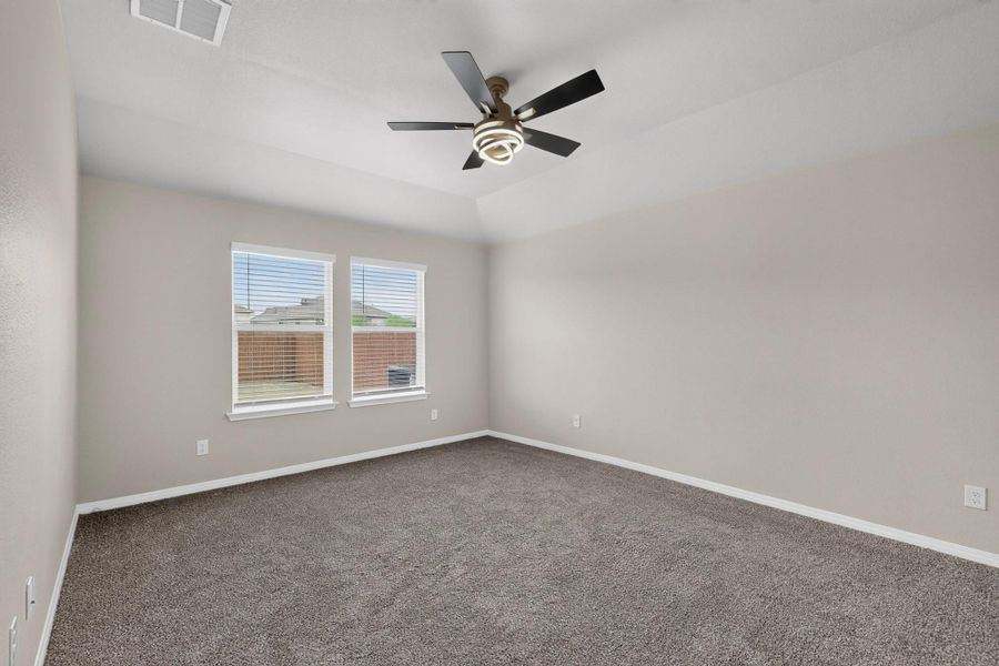 Plush carpeting anchors this spacious bedroom featuring a deeply recessed tray ceiling design.
