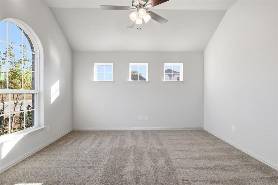 Empty room featuring lofted ceiling, light carpet, and ceiling fan Empty room featuring lofted ceiling, light carpet, and ceiling fan
