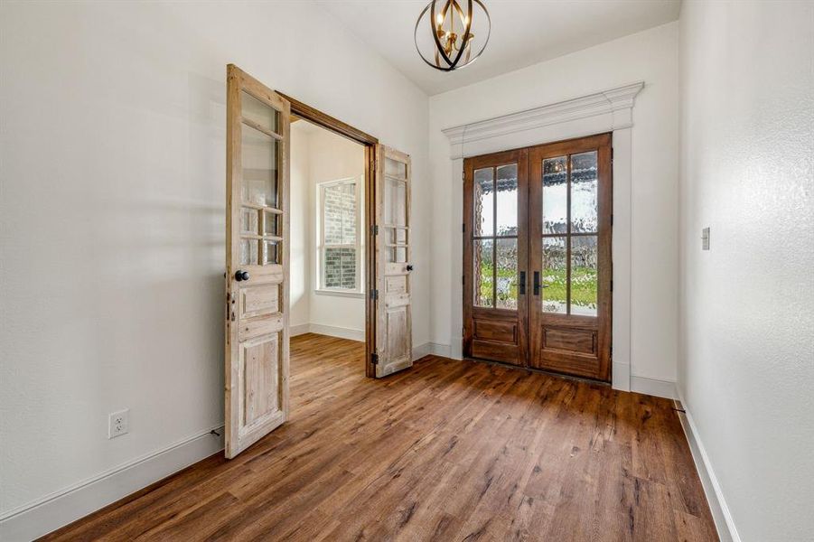 Entrance foyer with a notable chandelier, wood-type flooring, and french doors