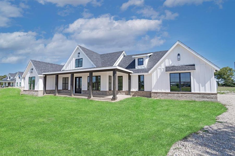 Rear view of property with roof with shingles, board and batten siding, and a yard
