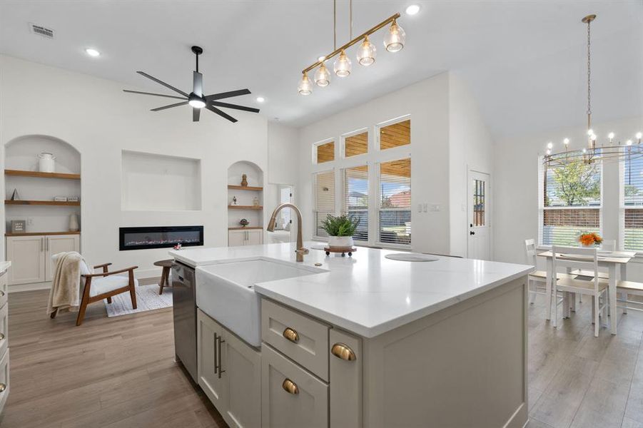 Kitchen with built in features, hanging light fixtures, light wood-style flooring, light stone countertops, and recessed lighting Kitchen with built in features, hanging light fixtures, light wood-style flooring, light stone countertops, and recessed lighting
