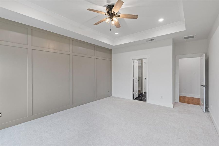 Unfurnished bedroom featuring recessed lighting, a tray ceiling, light colored carpet, and visible vents