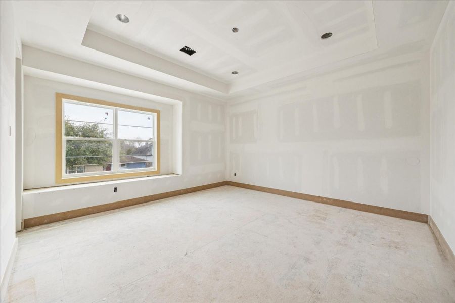 Spacious secondary bedroom with tray ceiling detail and a deep set window that draws in soft natural light. Generous wall space allows for flexible furniture placement while maintaining a bright, airy feel.