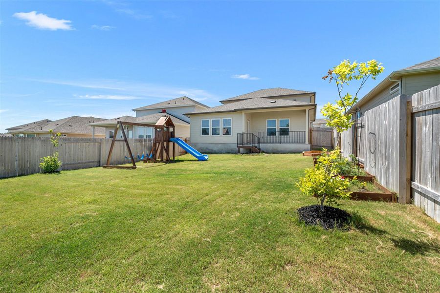 The large level backyard features a playscape and garden beds. The large level backyard features a playscape and garden beds.