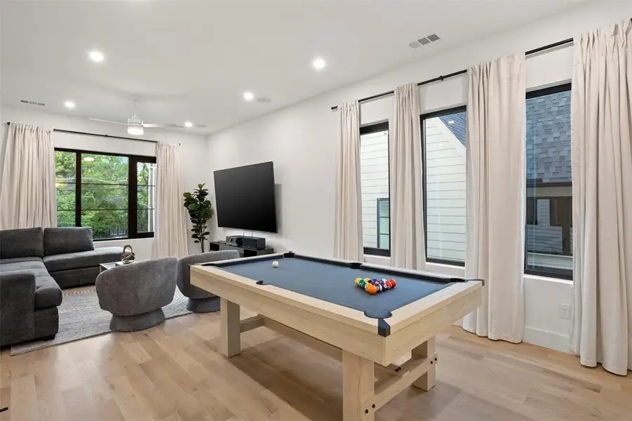 Recreational space featuring light wood-finish flooring and a ceiling fan with integrated lighting
